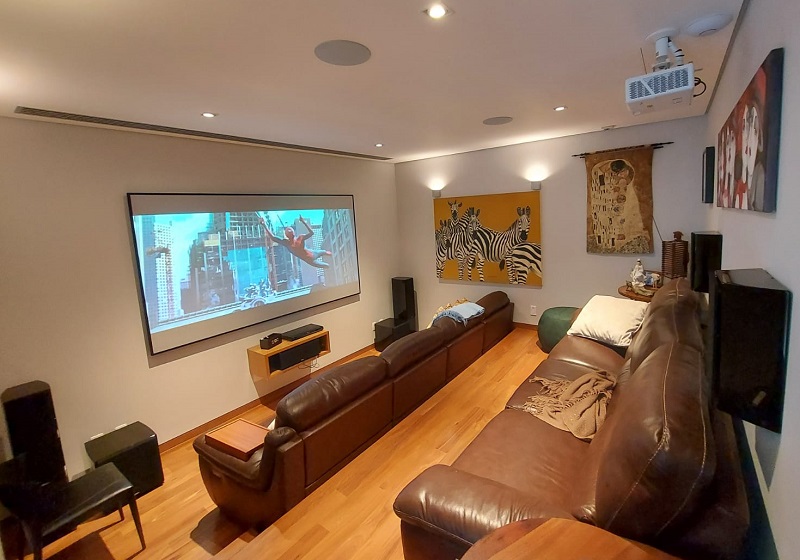 Sala de cinema em casa com sofás, home theater e projetor